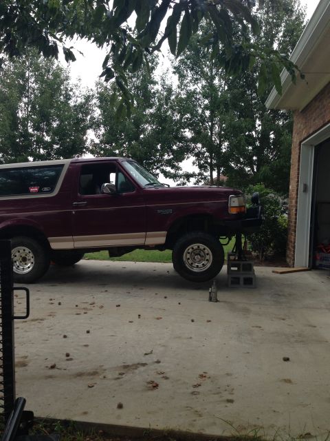 1996 Ford Bronco - A maroon Ford Bronco is elevated on jack stands, possibly for maintenance or modification.
