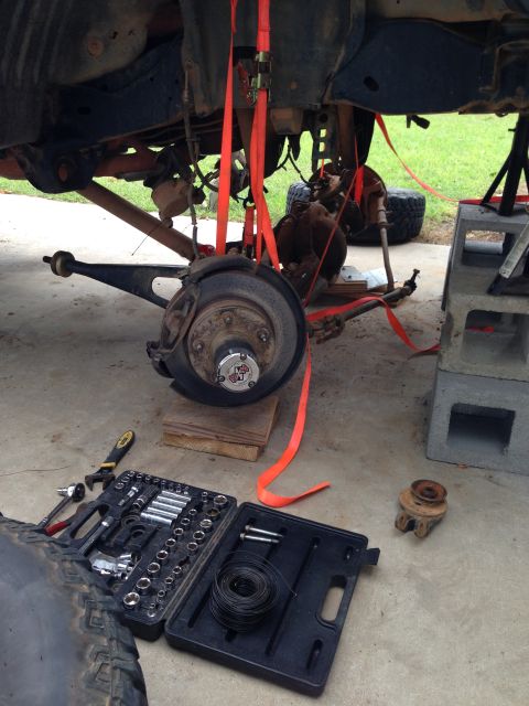 1996 Ford Bronco - The front suspension of a vehicle is being worked on, with tools laid out nearby.