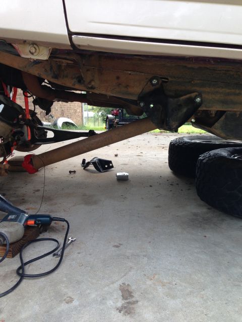 1996 Ford Bronco - The underside of a vehicle is shown with lift kit components and tools, with another vehicle visible in the background.
