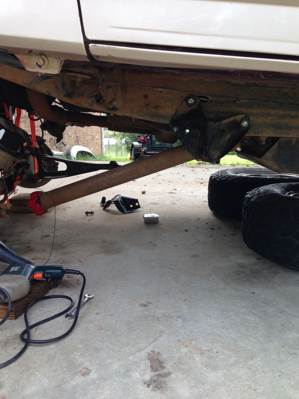 Vehicle underbody with lift kit parts, tools, and tires on concrete