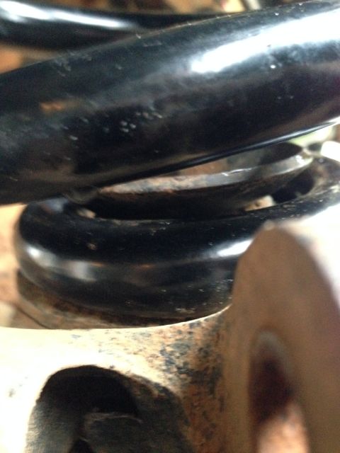 1996 Ford Bronco - Close-up of a black suspension spring and rusty metal bracket, likely part of a vehicle's lift kit installation.