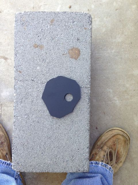 1996 Ford Bronco - A black metal part is placed on a cinder block, with a person's feet visible on either side.