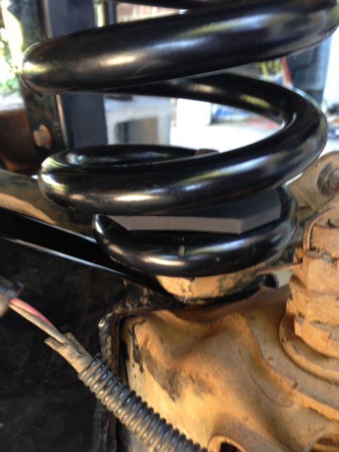 1996 Ford Bronco - A close-up view of a vehicle's suspension system, focusing on the coil spring and a spacer.