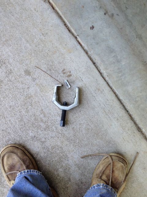 1996 Ford Bronco - A ball joint separator tool lies on concrete next to a person's feet, suggesting a repair or installation.