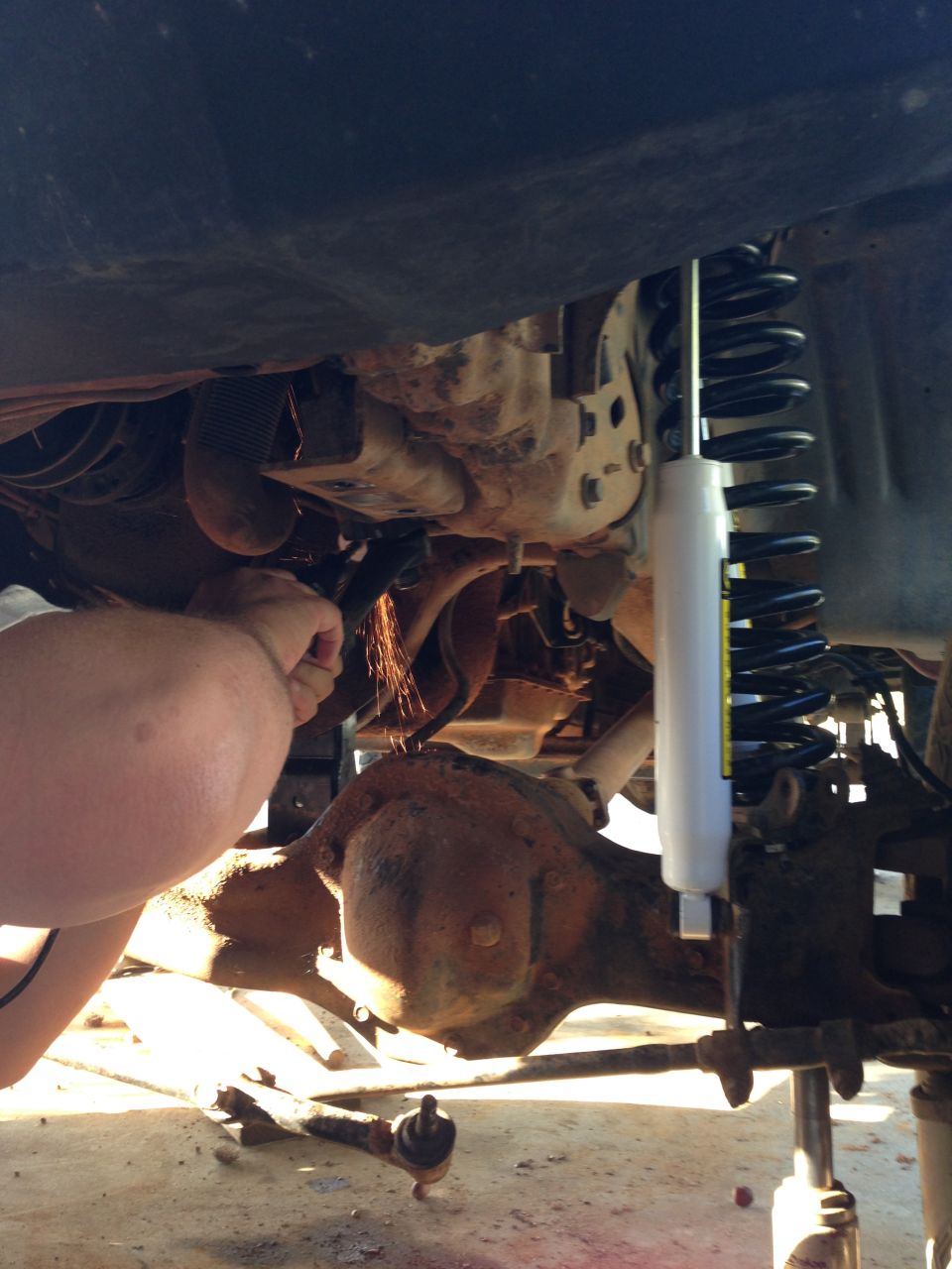 Person grinding on vehicle undercarriage near differential and new shock absorber