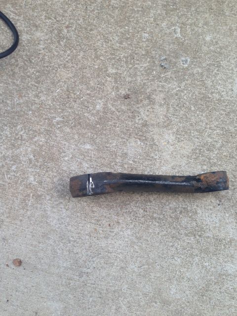 1996 Ford Bronco - A close-up view of a single, rusted metal component lying on a concrete surface.