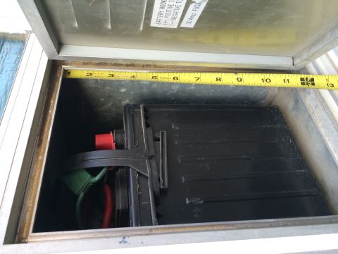1986 Yugo GV - A battery is secured within a metal box, with a tape measure indicating its size.