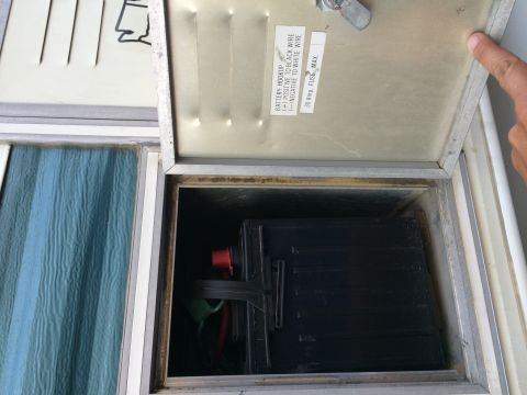 1986 Yugo GV - A close-up view of an open compartment reveals a battery and wiring, along with a label detailing hookup instructions and fuse information.