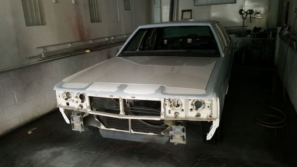 White Ford Crown Victoria with front end disassembled, in a garage