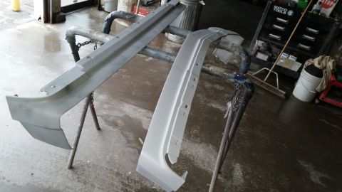 1991 Ford LTD Crown Victoria - Car bumper parts are prepped for painting in a workshop environment.