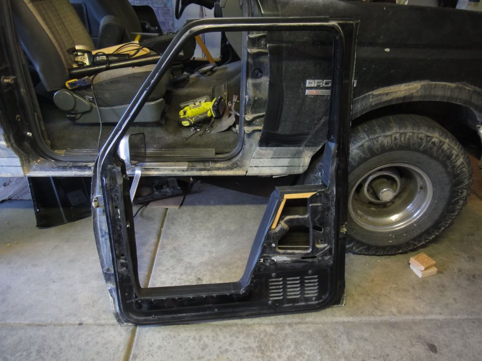 Driver's side door removed from a 1988 Ford Bronco, showing the interior and part of the exterior