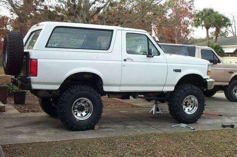 1995 Ford Bronco - White 1995 Ford Bronco lifted with aftermarket suspension and tires, parked next to another truck.