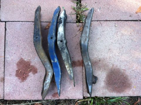 1968 Ford Torino - Collection of four curved metal car parts, possibly trim pieces, on a brick surface.