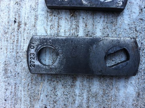 1968 Ford Torino - A metal bracket with stamped numbers and two holes is shown on a textured surface.