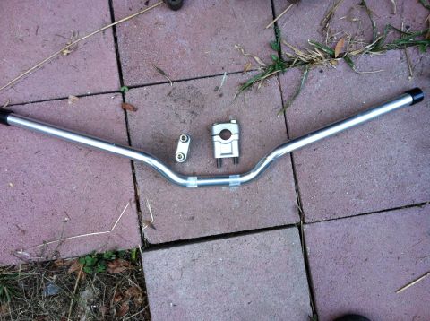 1968 Ford Torino - A set of silver motorcycle handlebars and a triple clamp are laid out on a paver surface.