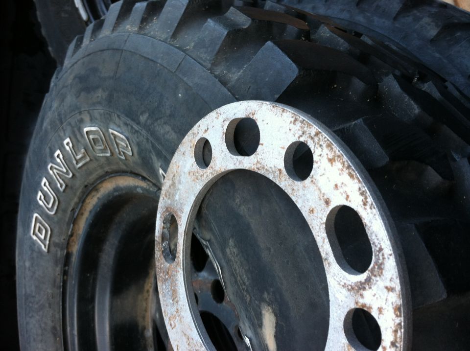 Dunlop tire next to a rusty wheel spacer with multiple bolt holes