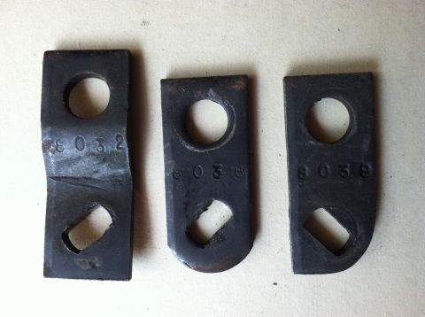 1968 Ford Torino - Three metal parts with stamped numbers are laid out on a surface.