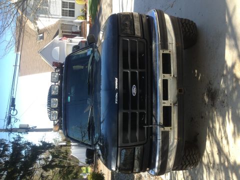1996 Ford Bronco - Front view of a black 1996 Ford Bronco, an aftermarket winch bumper and roof-mounted light bar.