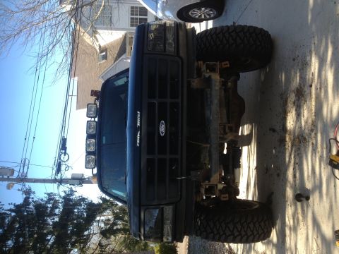 1996 Ford Bronco - Front view of a modified black Ford truck with a winch bumper and auxiliary lights, showing its lifted suspension and off-road tires.