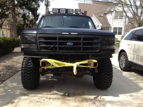 1996 Ford Bronco - This lifted truck features a custom front end with auxiliary lights and a tow strap attached to the bumper.