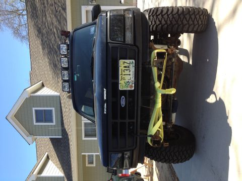 1996 Ford Bronco - Front view of a modified black Ford truck with a winch bumper and off-road tires.
