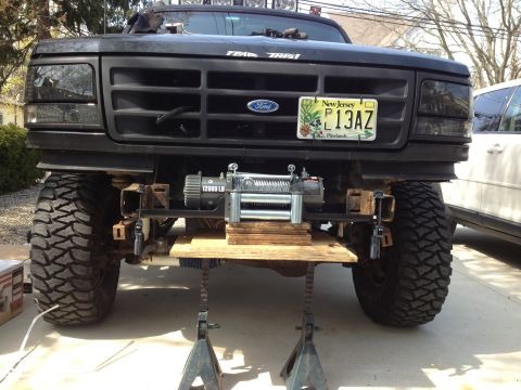 1996 Ford Bronco - A Ford truck is elevated on jack stands, displaying a newly installed winch assembly on its front end.