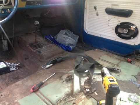 1971 Ford F-250 - Tools and a seatbelt lie on the exposed floor of a truck undergoing interior work.