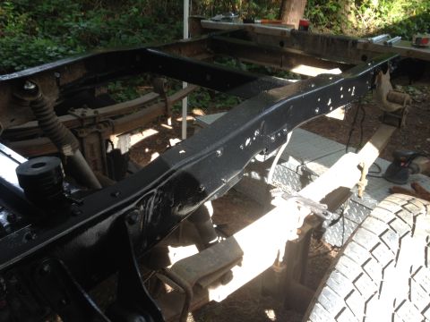 1971 Ford F-250 - The frame of a truck, showing leaf springs and a tire, appears to be undergoing restoration or repair.