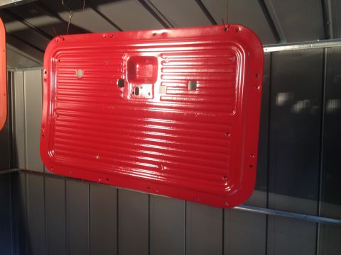 1971 Ford F-250 - Newly painted red truck door panel is ready for installation.