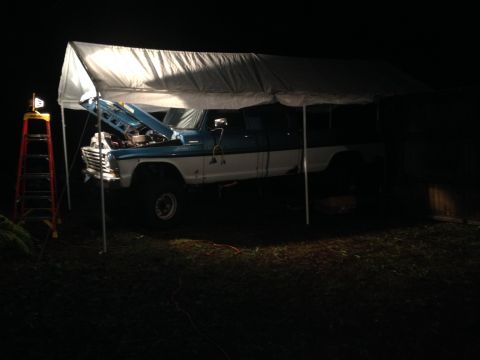 1971 Ford F-250 - A blue and white Ford pickup truck is parked under a canopy with its hood open at night.