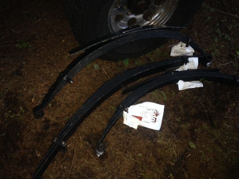 1971 Ford F-250 - Several leaf springs and a tire are laid out on the ground, suggesting a vehicle repair or parts sale.