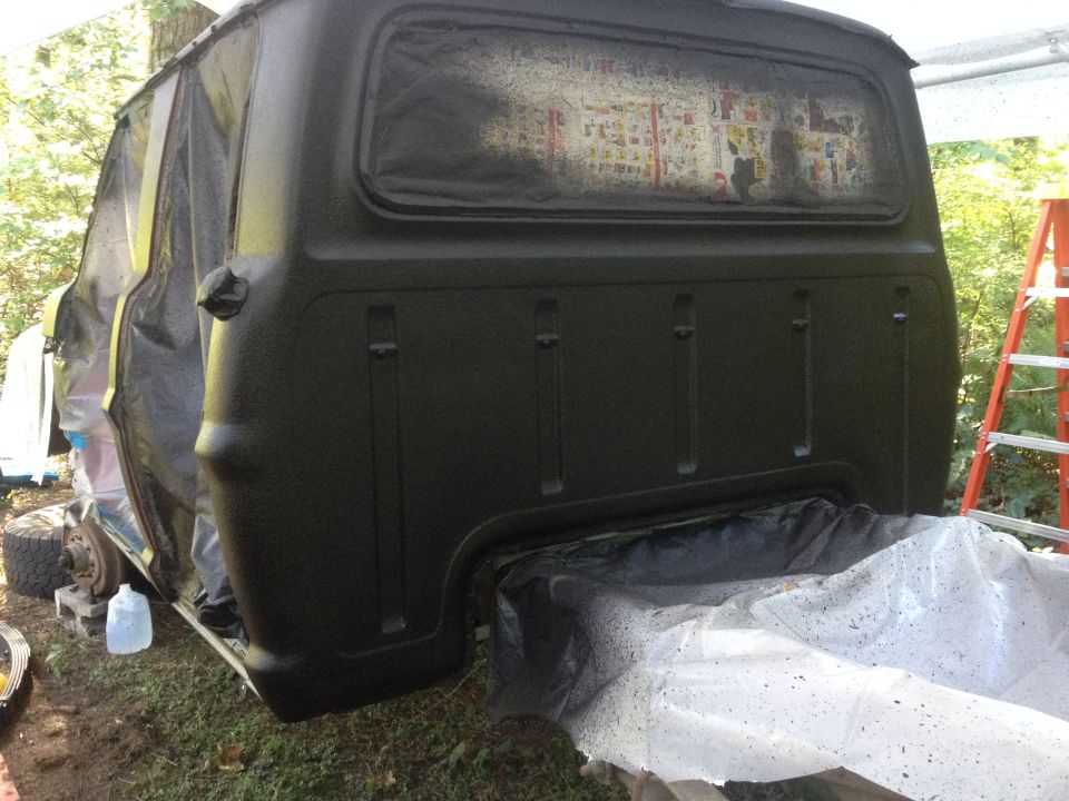 1971 Ford F-250 truck bed covered in plastic and being painted dark green