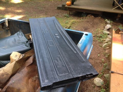 1971 Ford F-250 - A black Ford tailgate with embossed lettering is seen inside the bed of a blue pickup truck.