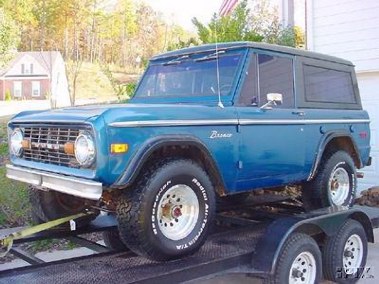 1996 Ford Bronco - This blue Ford Bronco is being transported on a trailer, showing its distinctive front grille.