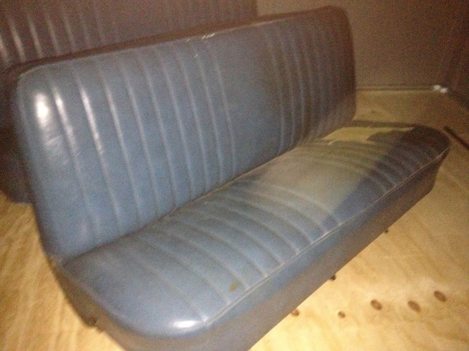 Blue vinyl bench seat with vertical pleats. Seat cushion is worn