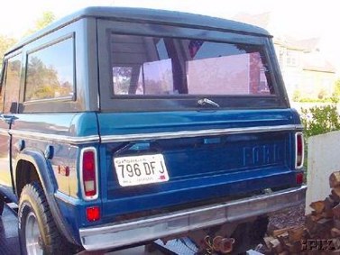 1996 Ford Bronco - Rear view of a blue Ford Bronco with tinted windows and a chrome bumper.
