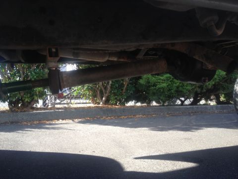 1971 Ford F-250 - A low-angle view shows the undercarriage of a truck, focusing on the driveshaft and exhaust components.