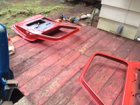1971 Ford F-250 - Disassembled red car doors lie on a weathered wooden deck outdoors.
