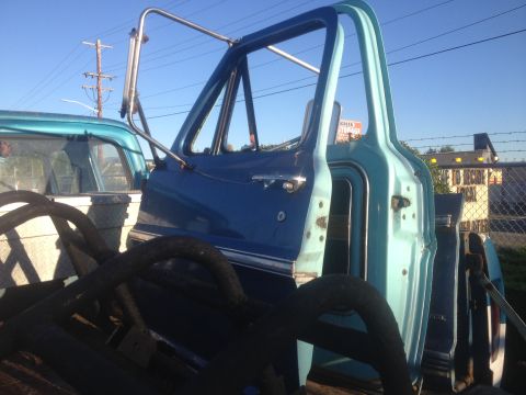 1971 Ford F-250 - Close-up of a truck's open cab door, with another vehicle partially visible beside it.