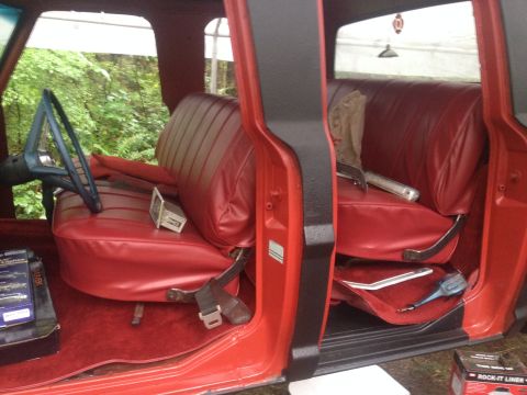 1971 Ford F-250 - Interior view of a truck's red bench seats and dashboard area, showing the driver's side.