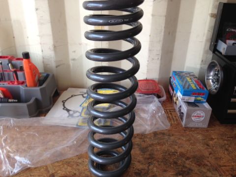 1996 Ford Bronco - A single coil spring is shown in a workshop setting with various tools and parts.