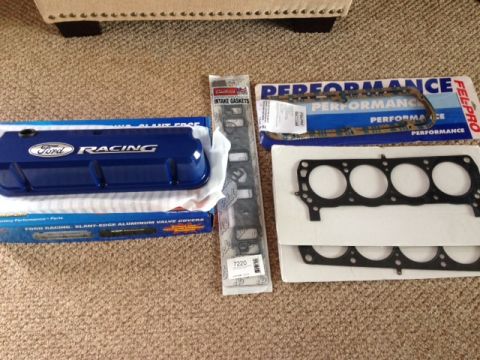 1996 Ford Bronco - Engine parts including Ford Racing valve covers and various gaskets are laid out on a carpeted surface.