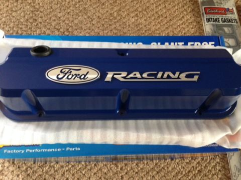 1996 Ford Bronco - Blue Ford Racing valve cover and Edelbrock intake gaskets are displayed on a carpeted surface.