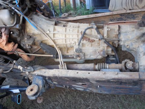 1993 Ford Bronco - Underside view of a truck/SUV chassis showing the automatic transmission and transfer case, driveshaft with U-joints, frame rail, and vario…
