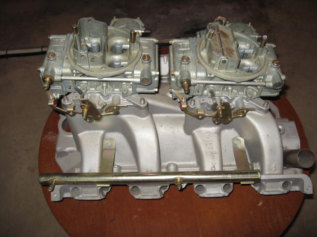 Aluminum intake manifold topped with dual four-barrel carburetors on a table