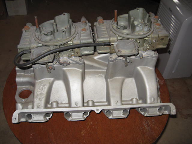 Aluminum dual carburetor intake manifold with two carburetors, part number visible