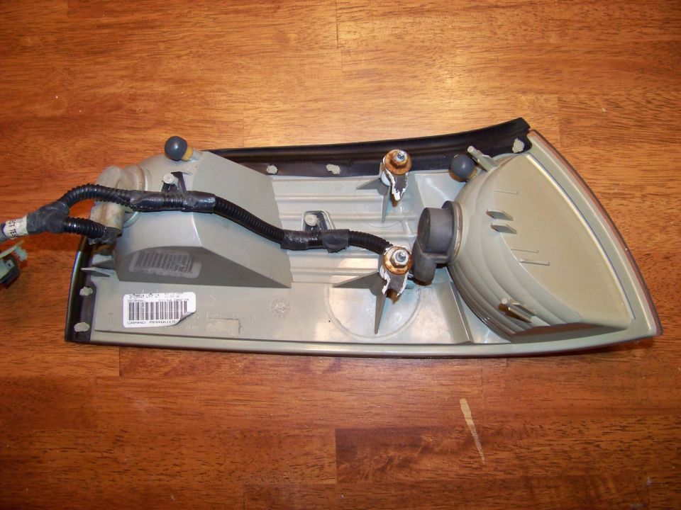 Back of a car tail light assembly with wiring harness and bulb sockets. Label visible