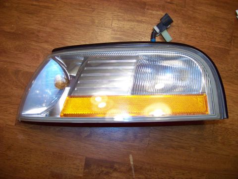 1995 Mercury Grand Marquis - This is a headlight assembly, likely for a car, shown on a wooden background.