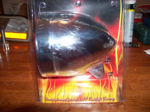 1995 Mercury Grand Marquis - A chrome headlight housing is packaged with flame graphics and text indicating it is a direct replacement.