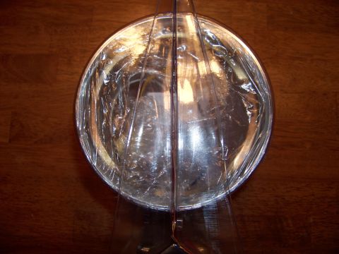 1995 Mercury Grand Marquis - Headlight reflector part, covered in protective plastic wrap, displayed on a wood grain background.